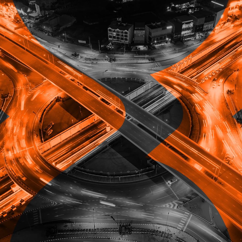 Foto de rotatória vista de cima em preto e branco com destaque em laranja do logotipo da Vex sobre ela
