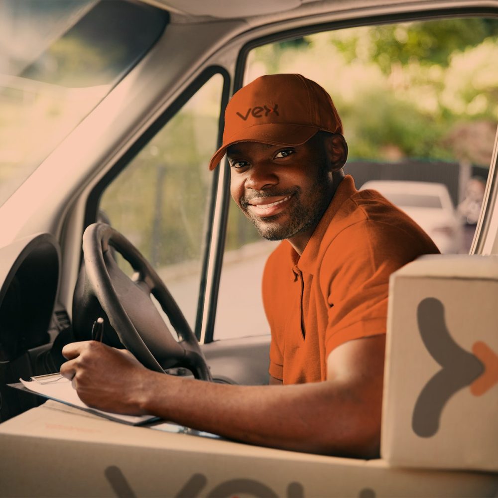 Homem apoiado em caixas com logotipo da Vex dentro de um caminhão